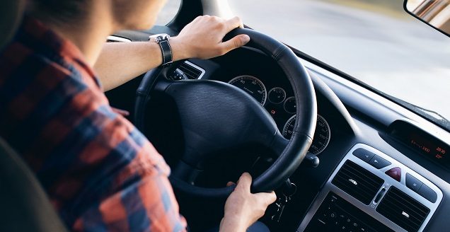 Young driver in his shirt in a nice modern car in motion